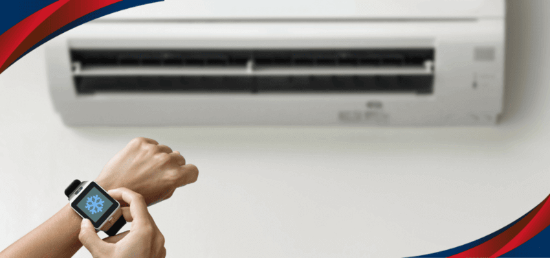 Person checking the indoor temperature using a smartwatch with a backdrop of an air conditioner, depicting American Home’s split type aircon unit